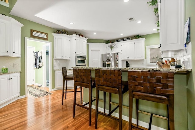 5720 NE Quartz Dr, Lees Summit, MO 64064 - kitchen with visible vents, a peninsula, appliances with stainless steel finishes, and white cabinets