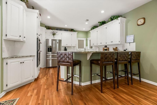 5720 NE Quartz Dr, Lees Summit, MO 64064 - kitchen featuring light stone countertops, white cabinets, a peninsula, light wood-style floors, and stainless steel appliances