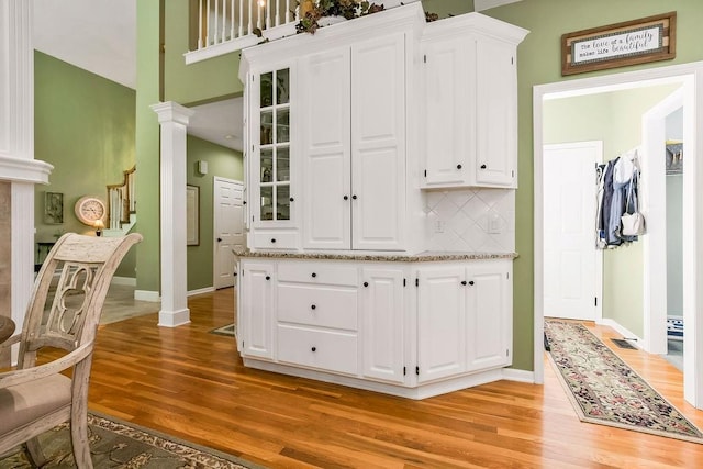 5720 NE Quartz Dr, Lees Summit, MO 64064 - kitchen with white cabinets, light wood-type flooring, and ornate columns