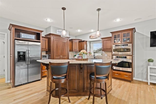 12544 Grand Ct, Kansas City, MO 64145 - kitchen featuring backsplash, light wood-style flooring, a kitchen island, and appliances with stainless steel finishes