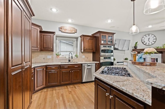 12544 Grand Ct, Kansas City, MO 64145 - kitchen with stainless steel appliances, a sink, tasteful backsplash, light wood-type flooring, and hanging light fixtures
