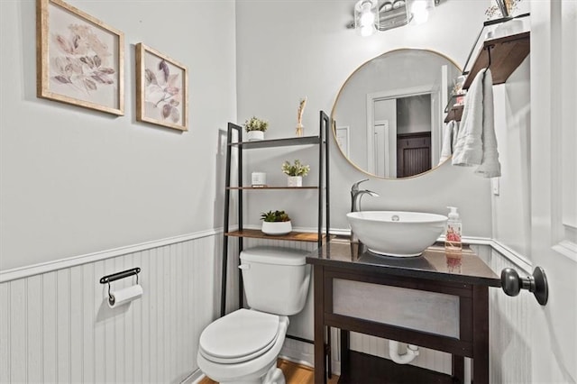 12544 Grand Ct, Kansas City, MO 64145 - half bathroom with toilet, vanity, and a wainscoted wall