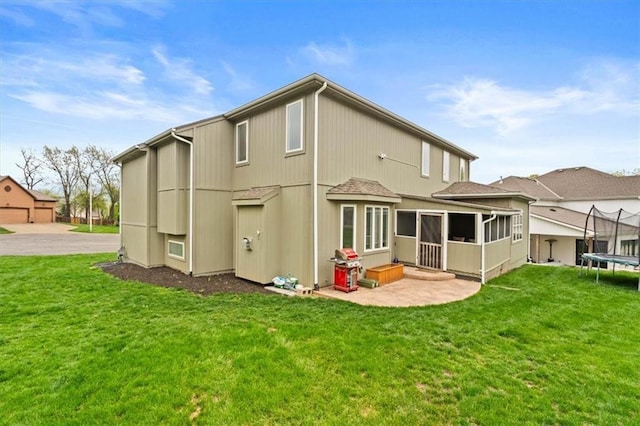12544 Grand Ct, Kansas City, MO 64145 - back of property featuring a sunroom, a yard, and a trampoline