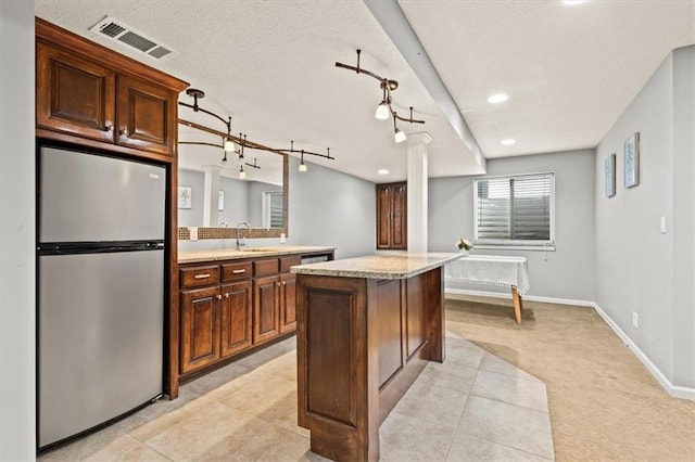 12544 Grand Ct, Kansas City, MO 64145 - kitchen featuring light carpet, a center island, a sink, visible vents, and freestanding refrigerator
