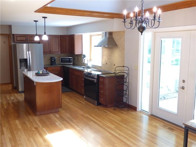 2405 W 123rd Ter, Leawood, KS 66209 - kitchen with wall chimney exhaust hood, stainless steel appliances, light wood-style flooring, a sink, and a chandelier