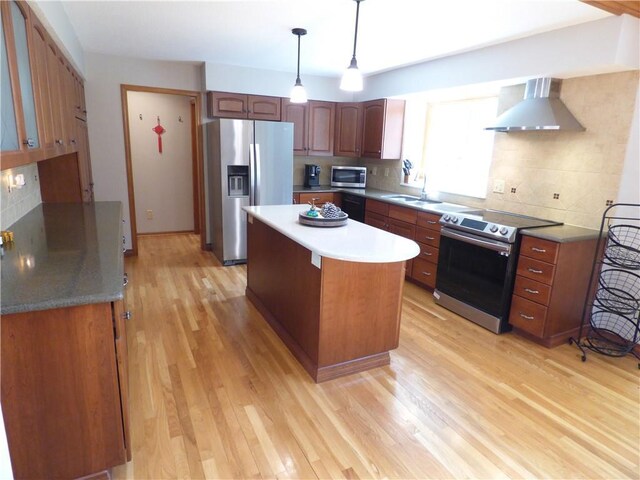 2405 W 123rd Ter, Leawood, KS 66209 - kitchen with light wood-type flooring, wall chimney range hood, appliances with stainless steel finishes, and decorative backsplash