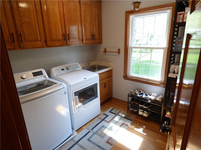 2405 W 123rd Ter, Leawood, KS 66209 - clothes washing area featuring washing machine and dryer, cabinet space, a sink, and light wood-style floors