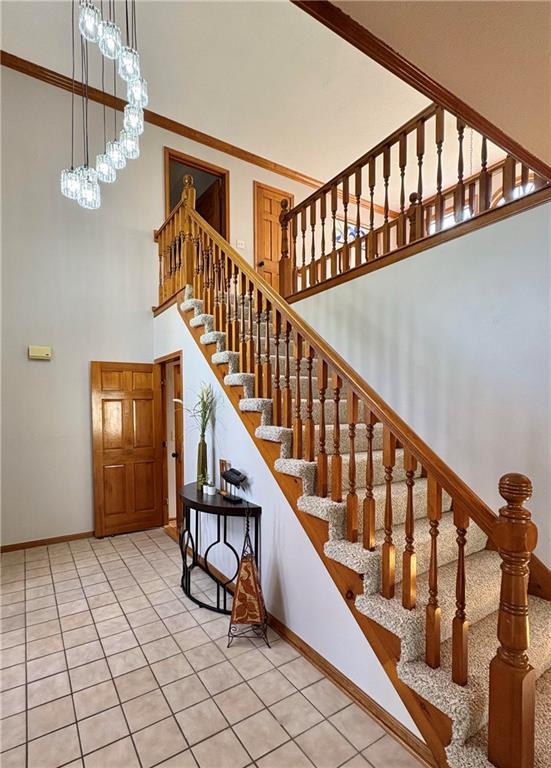 2405 W 123rd Ter, Leawood, KS 66209 - staircase featuring baseboards, a high ceiling, ornamental molding, and tile patterned floors