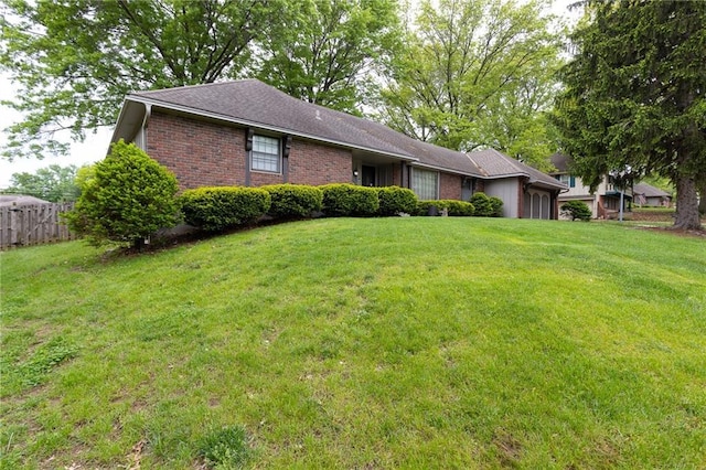 exterior space featuring brick siding, fence, a front lawn, and a garage