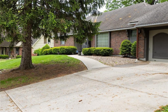 view of front facade with a front yard, a garage, brick siding, concrete driveway, and a shingled roof