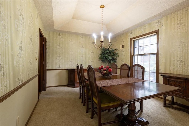 dining space featuring a raised ceiling, light colored carpet, wallpapered walls, and a chandelier