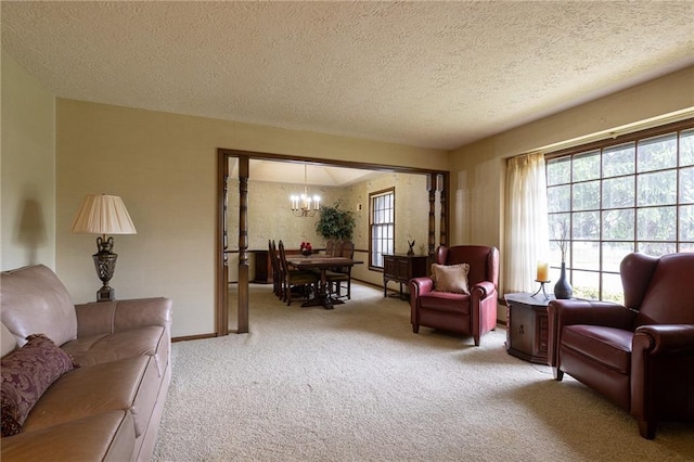 living area with carpet flooring, a textured ceiling, a notable chandelier, and plenty of natural light