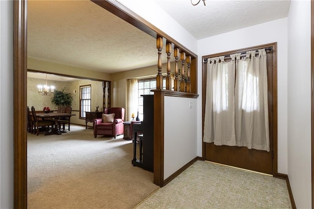 hallway with baseboards, carpet flooring, a textured ceiling, and a notable chandelier