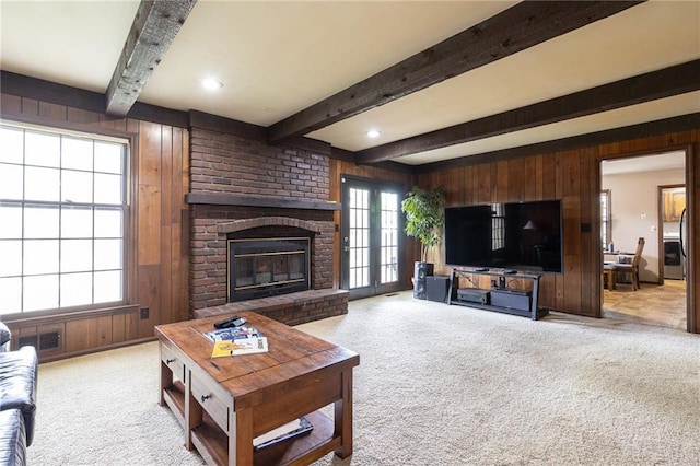 living area featuring carpet flooring, wooden walls, beam ceiling, and a fireplace