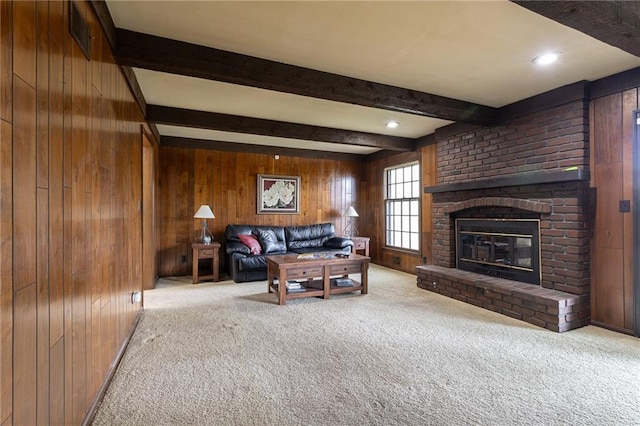 carpeted living room with wooden walls, beam ceiling, and a fireplace