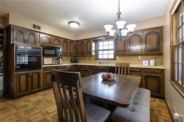 kitchen with visible vents, pendant lighting, light countertops, black appliances, and a notable chandelier