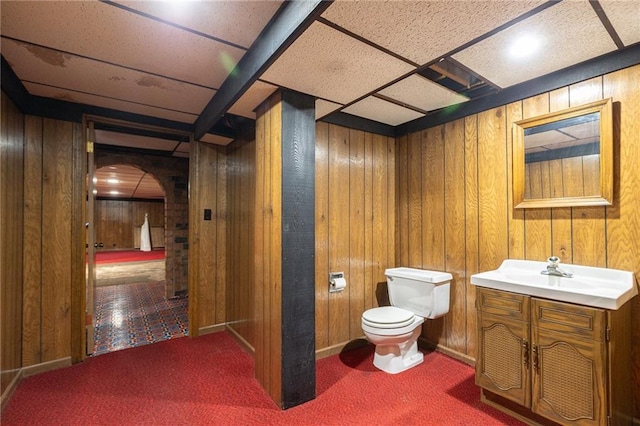 bathroom with vanity, wood walls, and toilet