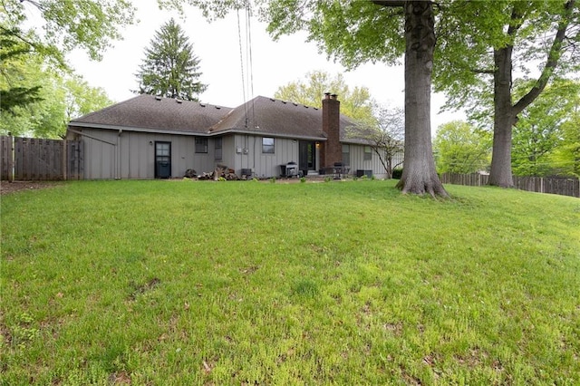 back of property with a yard, fence, and a chimney