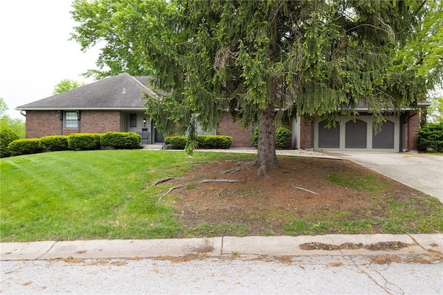 view of property hidden behind natural elements featuring brick siding, a garage, a front yard, and concrete driveway