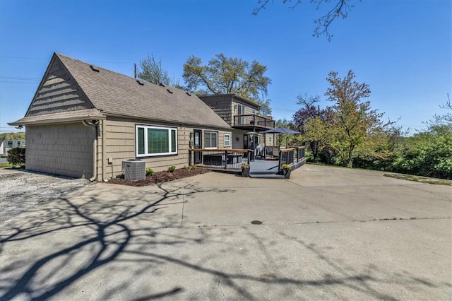 9501 Wornall Rd, Kansas City, MO 64114 - rear view of property featuring roof with shingles, a balcony, and central AC unit