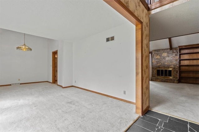 unfurnished room with baseboards, visible vents, a stone fireplace, and carpet