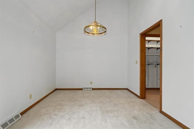 carpeted empty room with visible vents, baseboards, and high vaulted ceiling