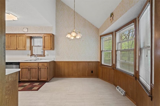 kitchen with visible vents, wood walls, wainscoting, lofted ceiling, and a sink