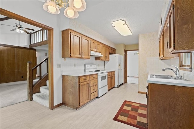 kitchen featuring brown cabinets, a sink, white appliances, light countertops, and under cabinet range hood