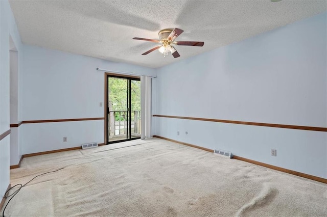 spare room with carpet, a ceiling fan, a textured ceiling, and visible vents