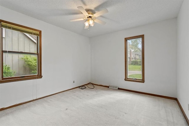 carpeted spare room featuring baseboards, a ceiling fan, and a textured ceiling