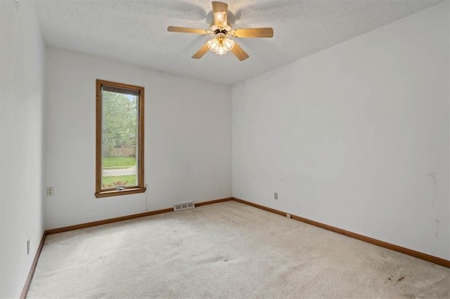 carpeted empty room with visible vents, a textured ceiling, ceiling fan, and baseboards