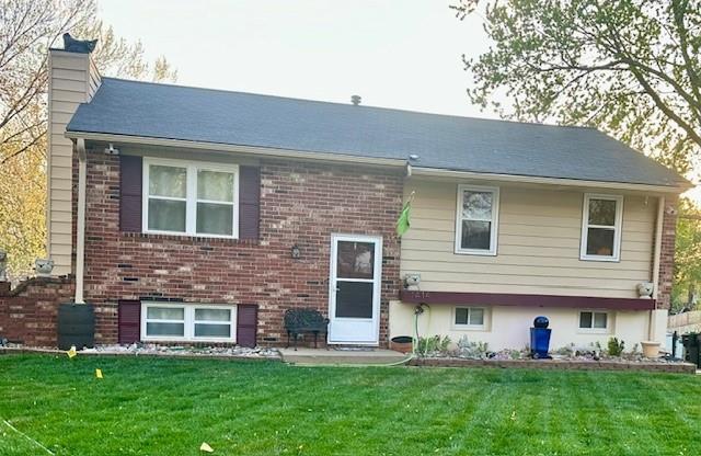 view of front of property featuring brick siding, a chimney, and a front yard