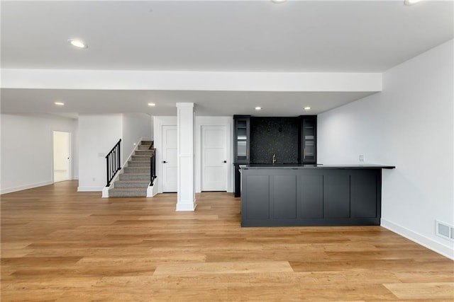 interior space with stairway, light wood finished floors, baseboards, wet bar, and recessed lighting