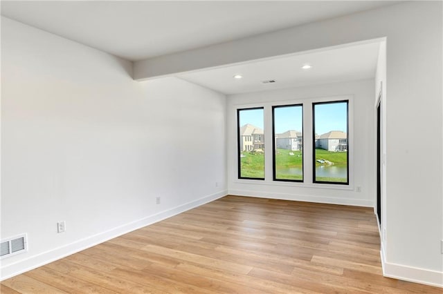 empty room with baseboards, light wood finished floors, visible vents, and recessed lighting