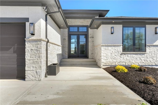 view of exterior entry with stone siding, french doors, and stucco siding