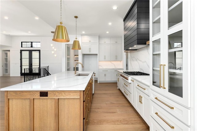 kitchen with french doors, light wood-style flooring, a sink, a large island, and custom exhaust hood