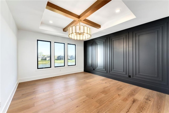 spare room featuring light wood-type flooring, coffered ceiling, baseboards, a notable chandelier, and beam ceiling