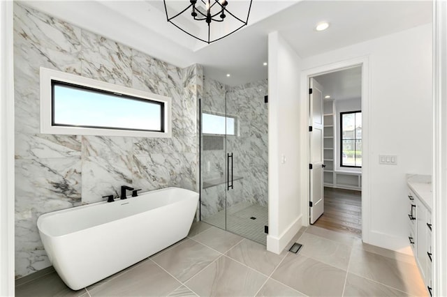 full bath featuring a marble finish shower, vanity, a freestanding tub, a chandelier, and recessed lighting