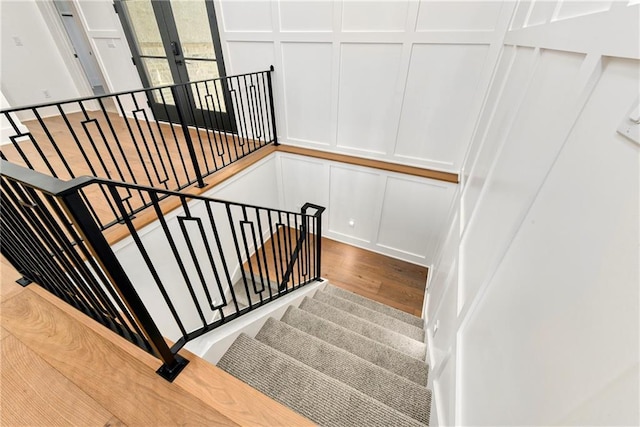 staircase featuring a decorative wall and wood finished floors