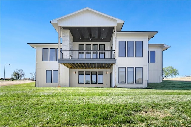 rear view of house featuring a balcony and a yard