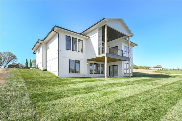 rear view of house featuring a lawn and a balcony