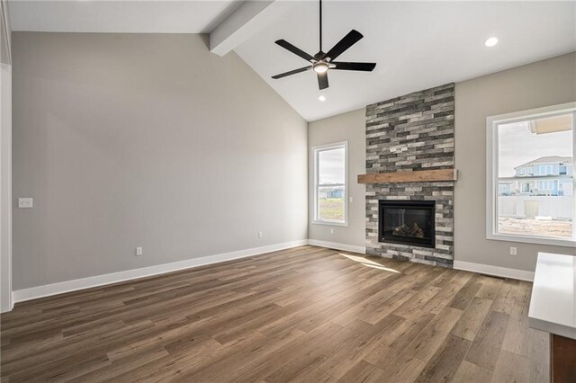 25016 W 89th Ter, Lenexa, KS 66227 - unfurnished living room with a ceiling fan, beamed ceiling, wood finished floors, a stone fireplace, and high vaulted ceiling