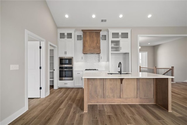 25016 W 89th Ter, Lenexa, KS 66227 - kitchen featuring stainless steel oven, black microwave, custom exhaust hood, a center island with sink, and dark wood-style floors