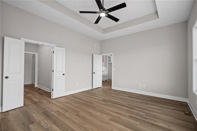 25016 W 89th Ter, Lenexa, KS 66227 - unfurnished bedroom featuring wood finished floors, a tray ceiling, and ceiling fan