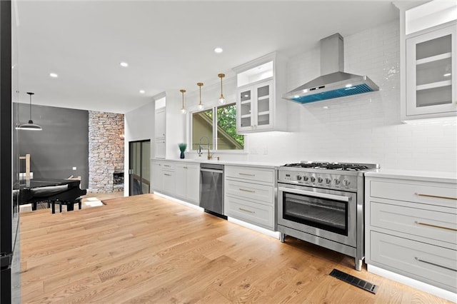 224 NW Locust St, Lees Summit, MO 64064 - kitchen with wall chimney range hood, appliances with stainless steel finishes, backsplash, decorative light fixtures, and recessed lighting