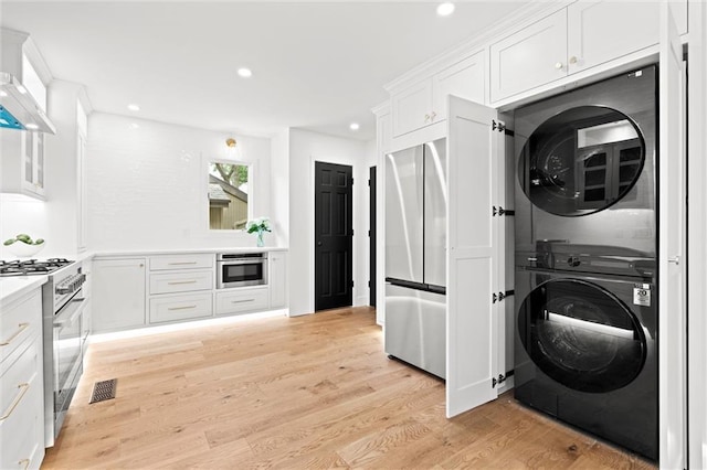 224 NW Locust St, Lees Summit, MO 64064 - laundry room featuring stacked washer / dryer, recessed lighting, and light wood-type flooring