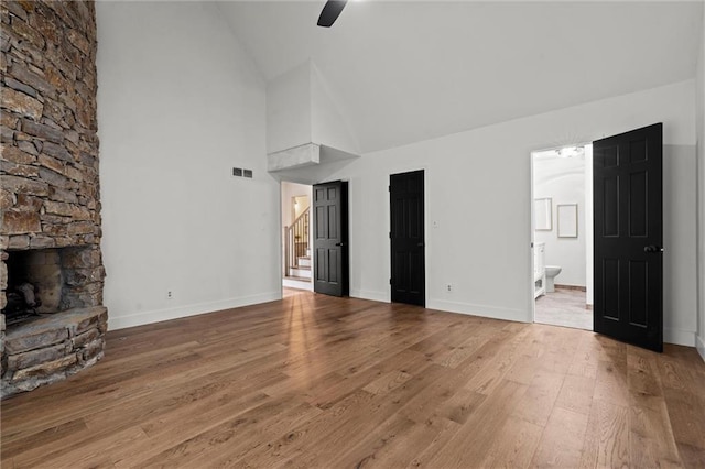 224 NW Locust St, Lees Summit, MO 64064 - unfurnished living room with wood finished floors, high vaulted ceiling, stairs, a stone fireplace, and ceiling fan