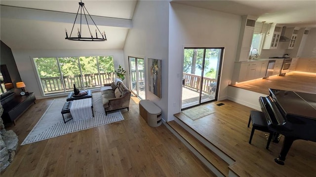 224 NW Locust St, Lees Summit, MO 64064 - living room featuring healthy amount of natural light, wood finished floors, a towering ceiling, and a chandelier