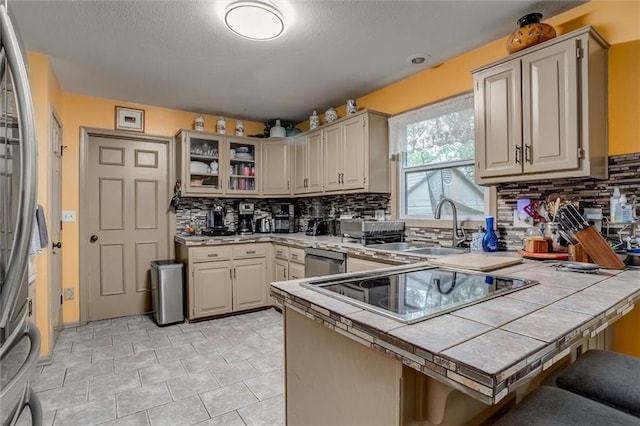 653 NE Reed Xing, Lees Summit, MO 64086 - kitchen with backsplash, tile countertops, a sink, a peninsula, and stainless steel appliances