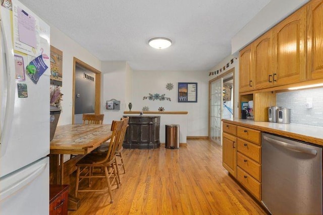 108 Sunrise Ct, Ozawkie, KS 66070 - kitchen with stainless steel dishwasher, tasteful backsplash, light wood-type flooring, and freestanding refrigerator